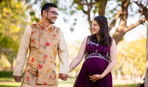 A young man and a young pregnant woman dressed in festive wears walking happily